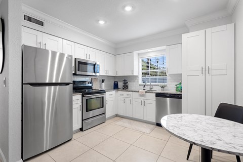A modern kitchen with a stainless steel refrigerator and white cabinets.