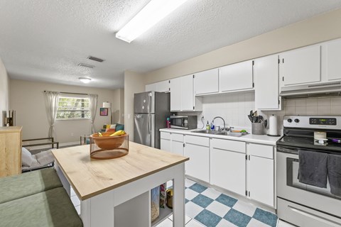 A kitchen with white cabinets and a wooden island.