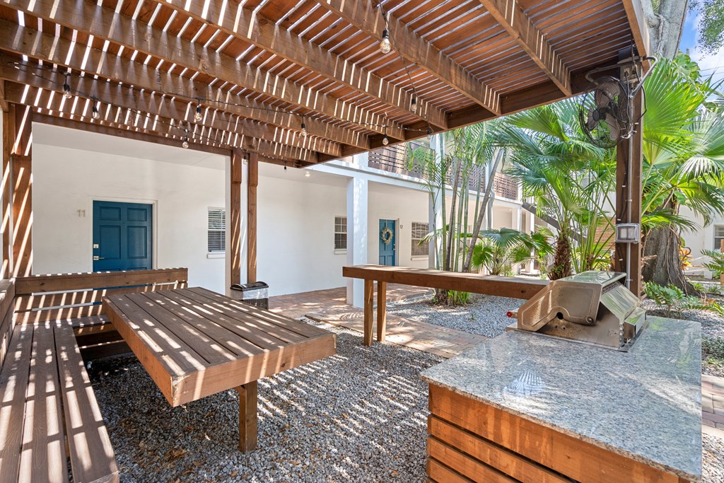 a covered patio with a picnic table and grill