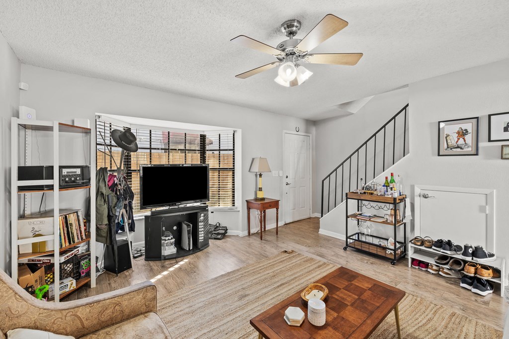 a living room with a ceiling fan and a tv