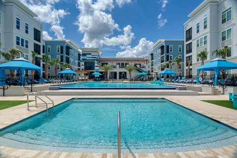 Resort style pool deck with blue umbrellas and spa at Ciel Luxury Apartments, Jacksonville