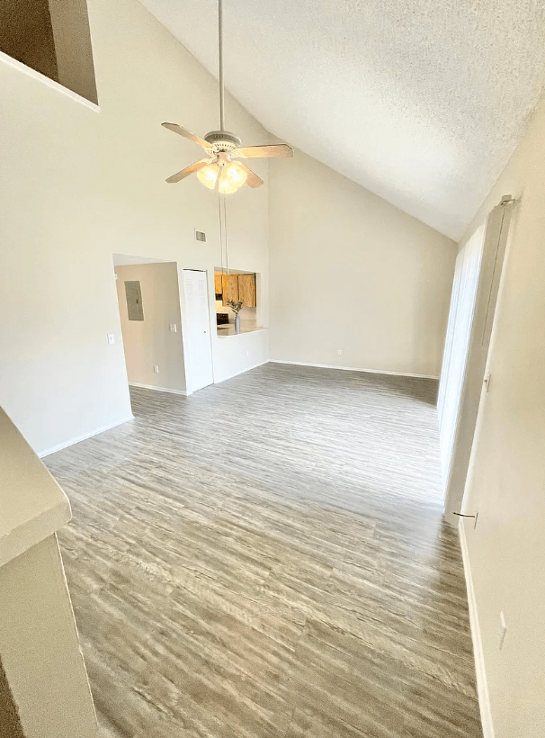 an empty living room with a ceiling fan