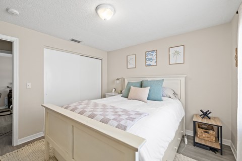 A bedroom with a bed, pillows, and pictures on the wall.