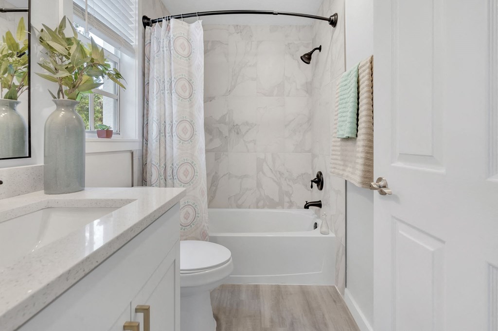 a bathroom with a white sink and toilet and a white bathtub with a shower curtain and