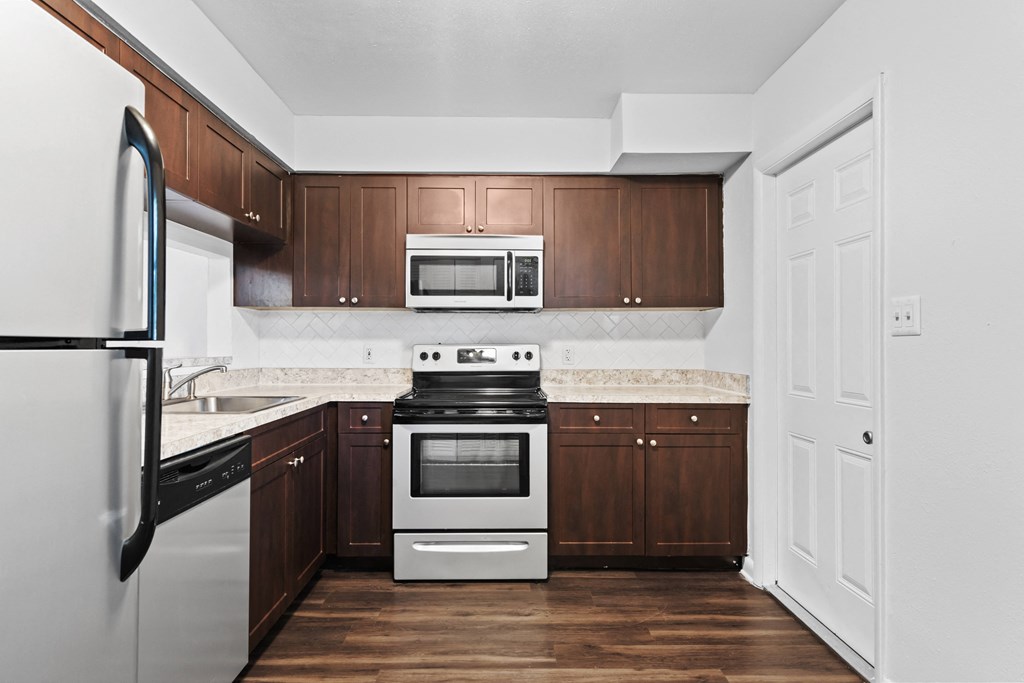 a kitchen with dark wood cabinets and stainless steel appliances