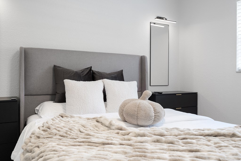 a bedroom with white walls and a large bed with a beige blanket on top of it