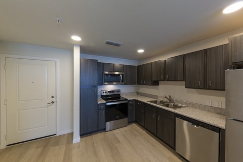 A modern kitchen with dark wood cabinets and stainless steel appliances.