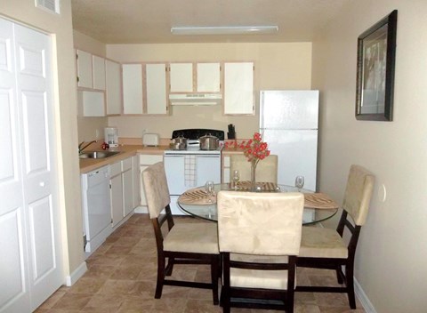 A kitchen with a table set for two with a vase of flowers on it.