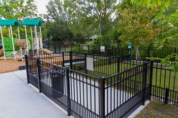 A playground with a green slide and a black fence.