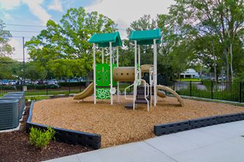 A playground with a green slide and a brown sandbox.