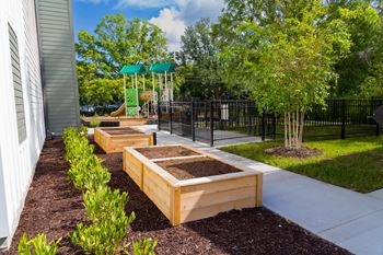 A row of wooden planters are lined up on a sidewalk.