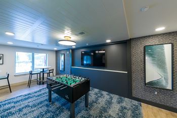 A foosball table is in the middle of a room with a blue rug.