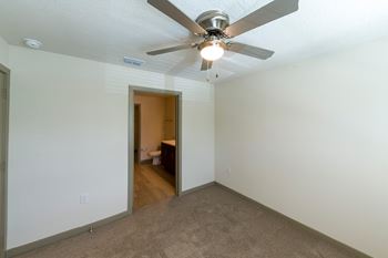 A room with a ceiling fan and carpeted floor.