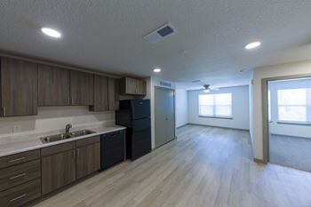 A kitchen with wooden cabinets and a black refrigerator.