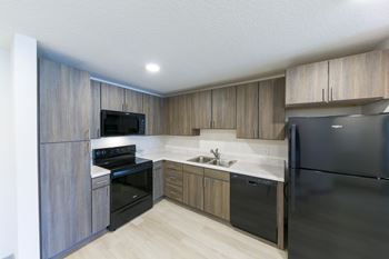 A modern kitchen with wooden cabinets and black appliances.