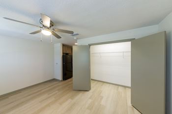 A room with a ceiling fan and a refrigerator.