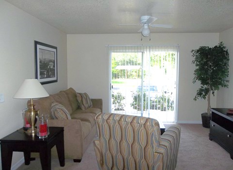 A living room with a couch, chair, and a table with a lamp on it.