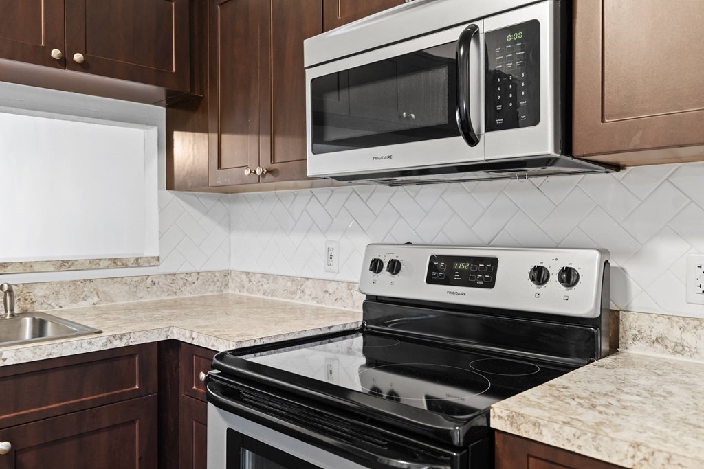 a kitchen with mahogany cabinets and a black and white stove top oven