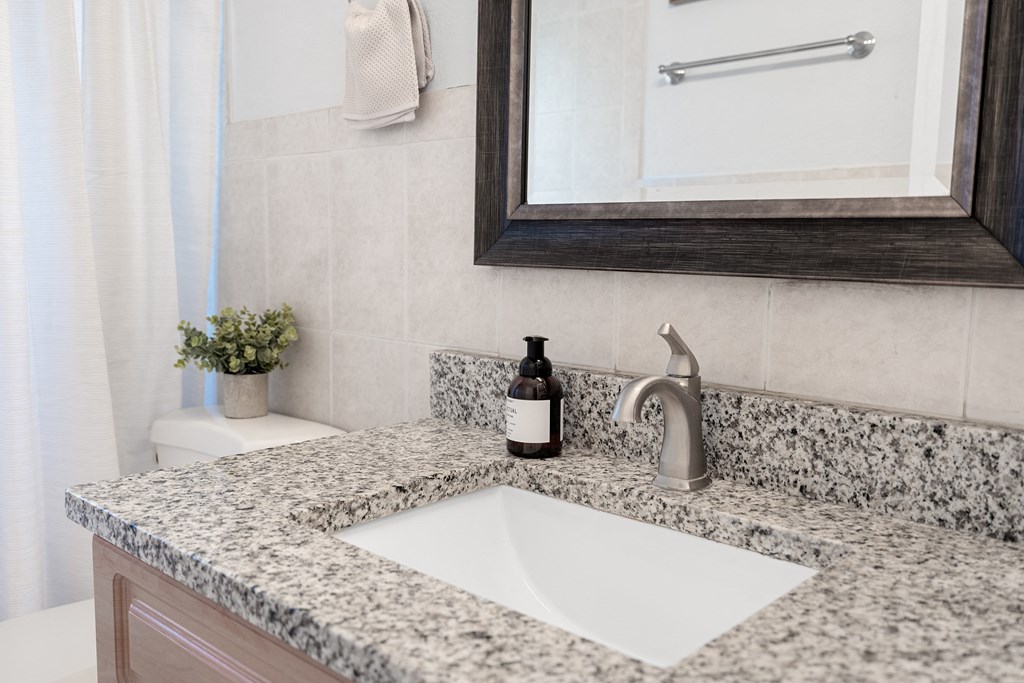 a bathroom sink with a mirror and toilet in a 555 waverly unit