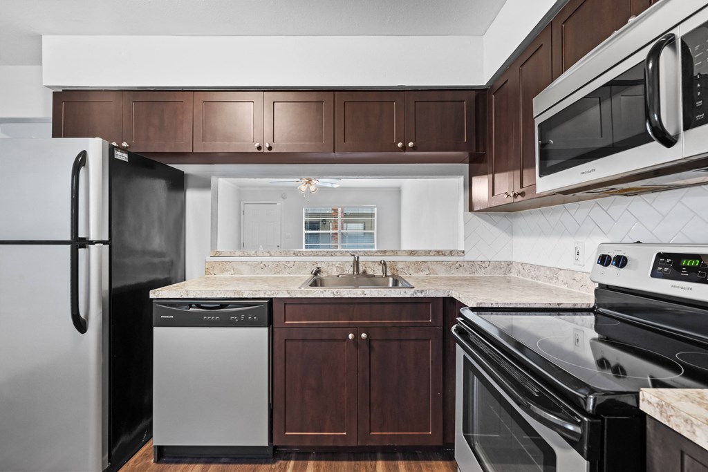 a kitchen with dark wood cabinets and white countertops