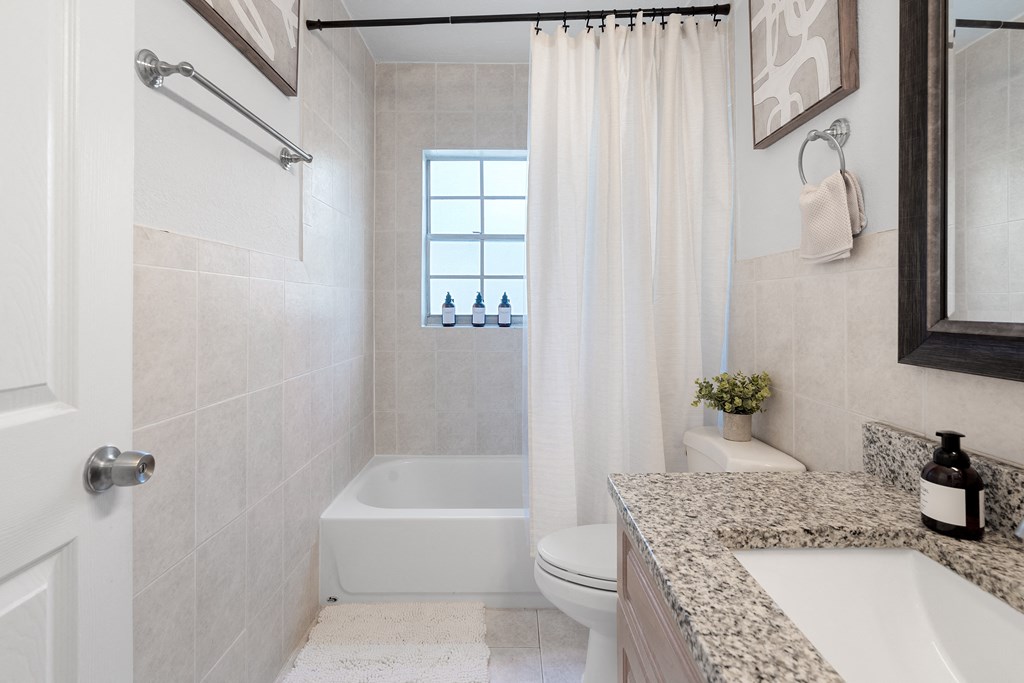 a bathroom with a white toilet next to a bathtub with a shower curtain