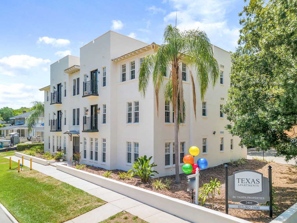 BC Tampa's Texas Ave Exterior Building a white building with palm trees in front of it