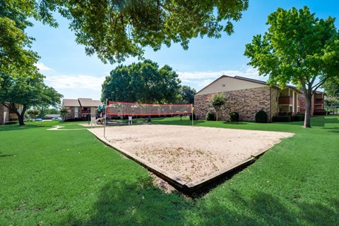 the yard has a volleyball court and a playground in front of a house