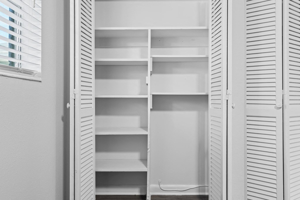 an empty closet with white shutters