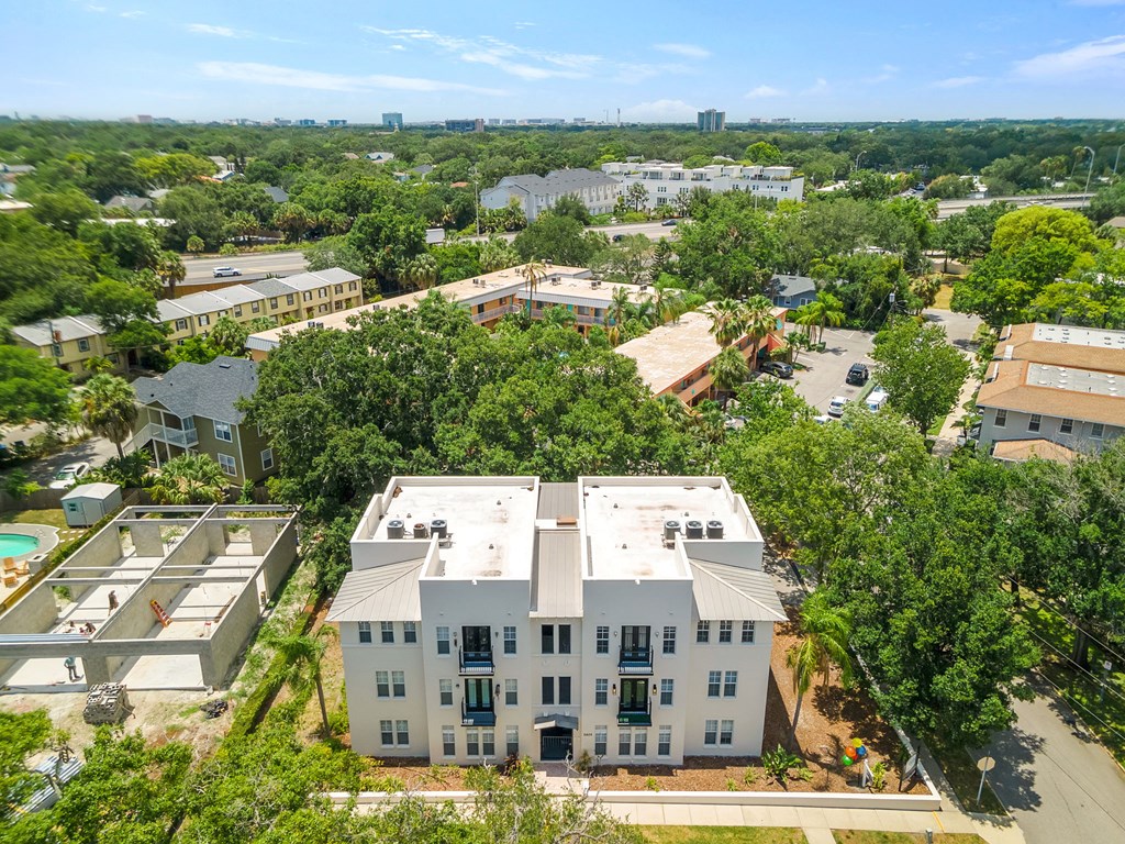 an aerial view of a large white building with a pool in front of it