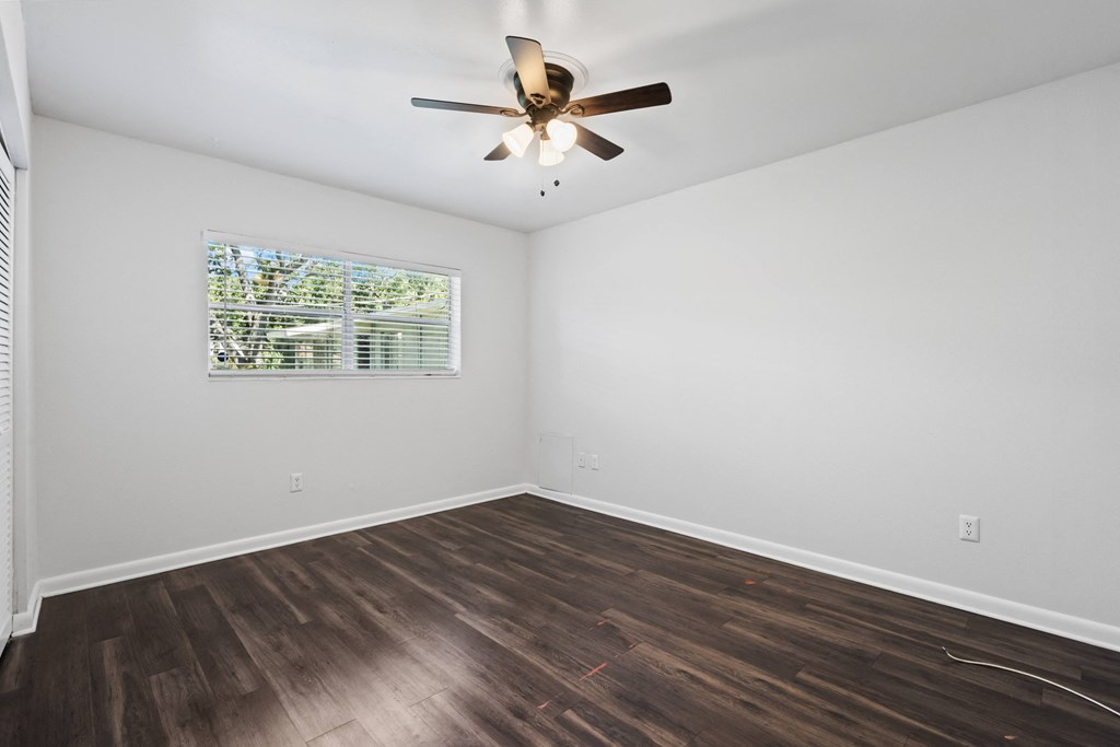 a bedroom with hardwood floors and a ceiling fan