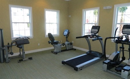 a gym with exercise equipment and three windows