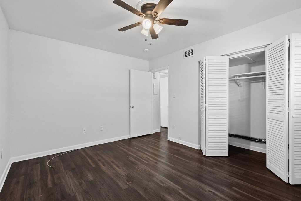 a bedroom with hardwood floors and a ceiling fan