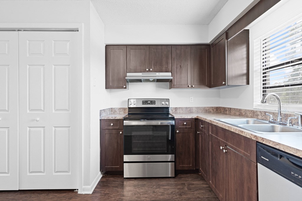 a kitchen with dark wood cabinets and stainless steel appliances