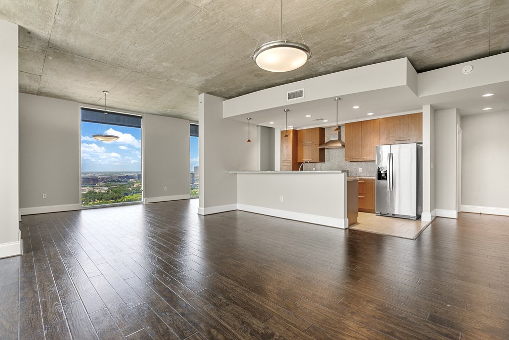 Empty living room with kitchen and large window offering city views in Houston, TX