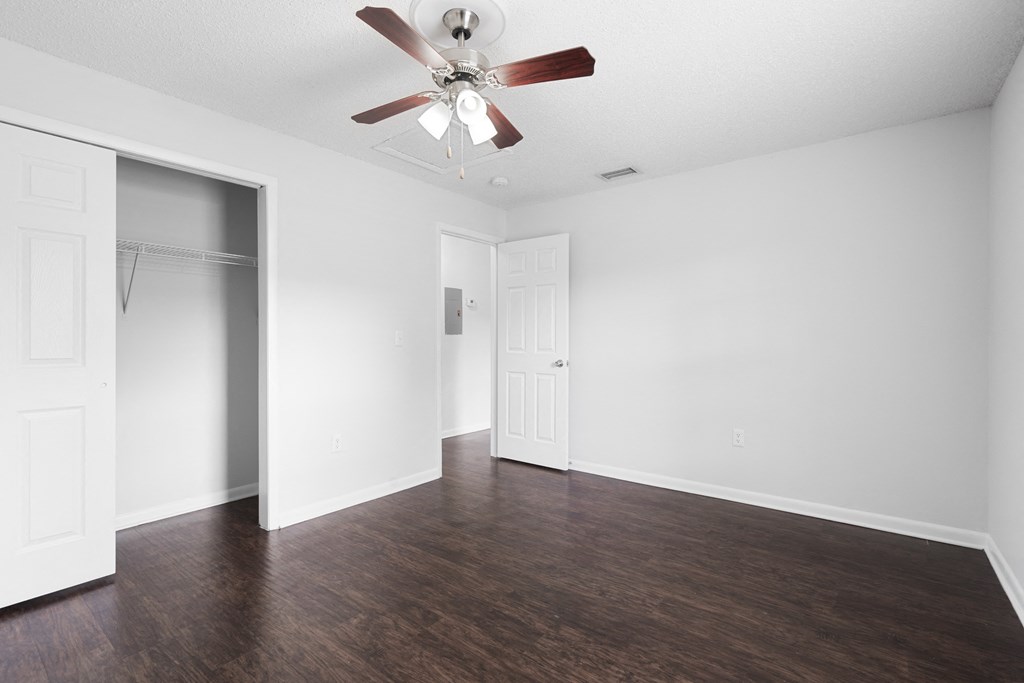 an empty bedroom with a ceiling fan and closet