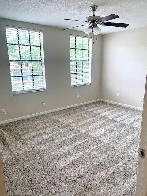 an empty room with a ceiling fan and two windows
