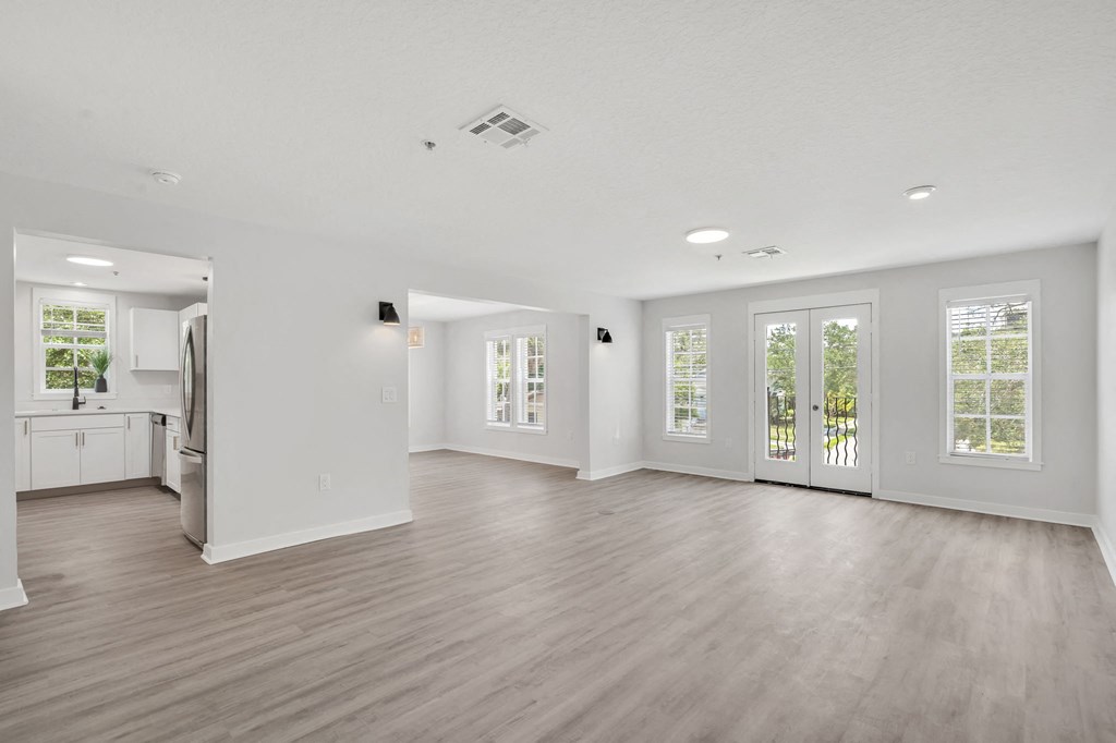 an empty living room with a kitchen in the background