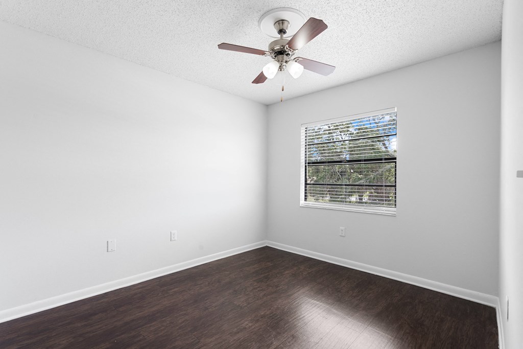 an empty bedroom with a ceiling fan and a window
