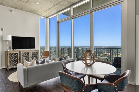 A living room with a grey couch, a round table and a television.
