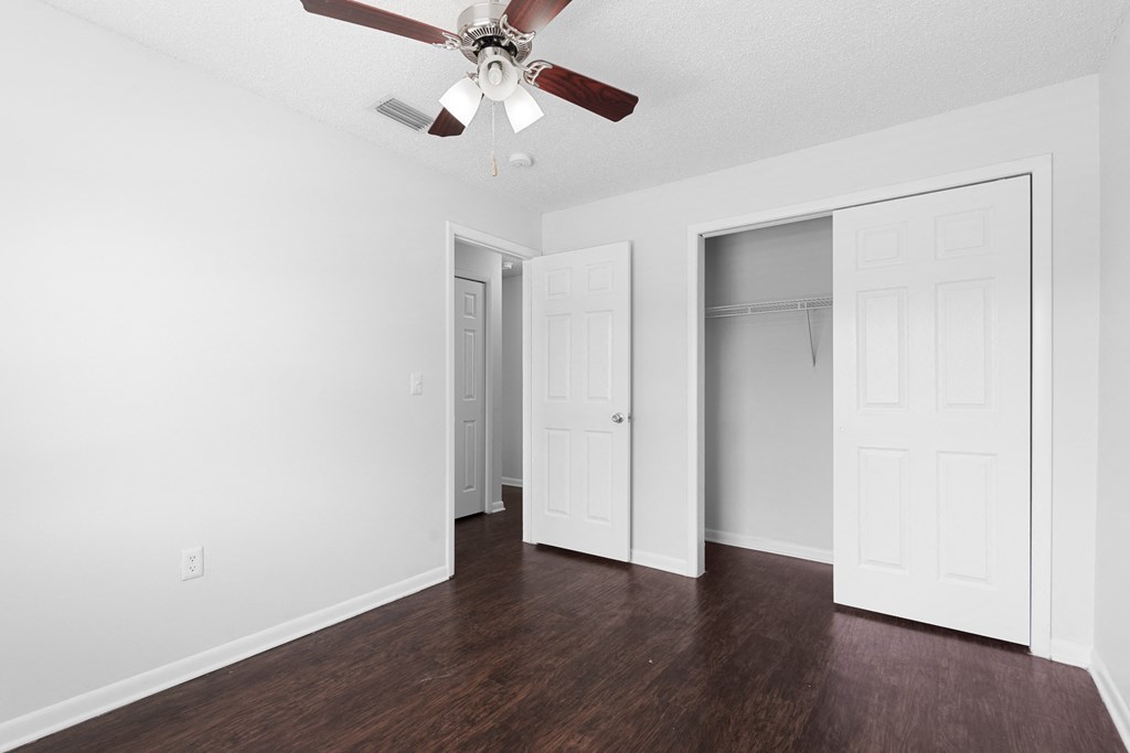 an empty bedroom with a ceiling fan and closet