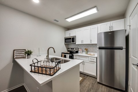 an open kitchen with stainless steel appliances and a white counter top