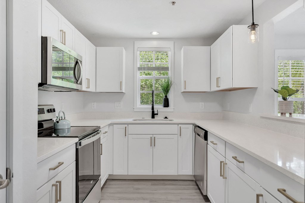 a white kitchen with white cabinets and stainless steel appliances
