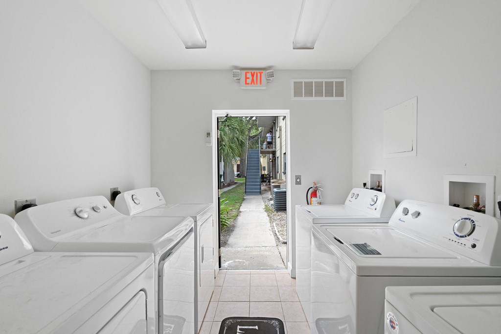a laundry room with white washers and dryers