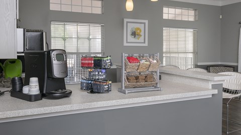 A kitchen counter with a coffee maker, a basket of bread, and a green cup on it.