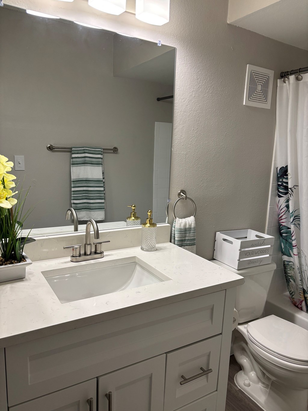 A white bathroom with a sink, toilet, and a mirror.