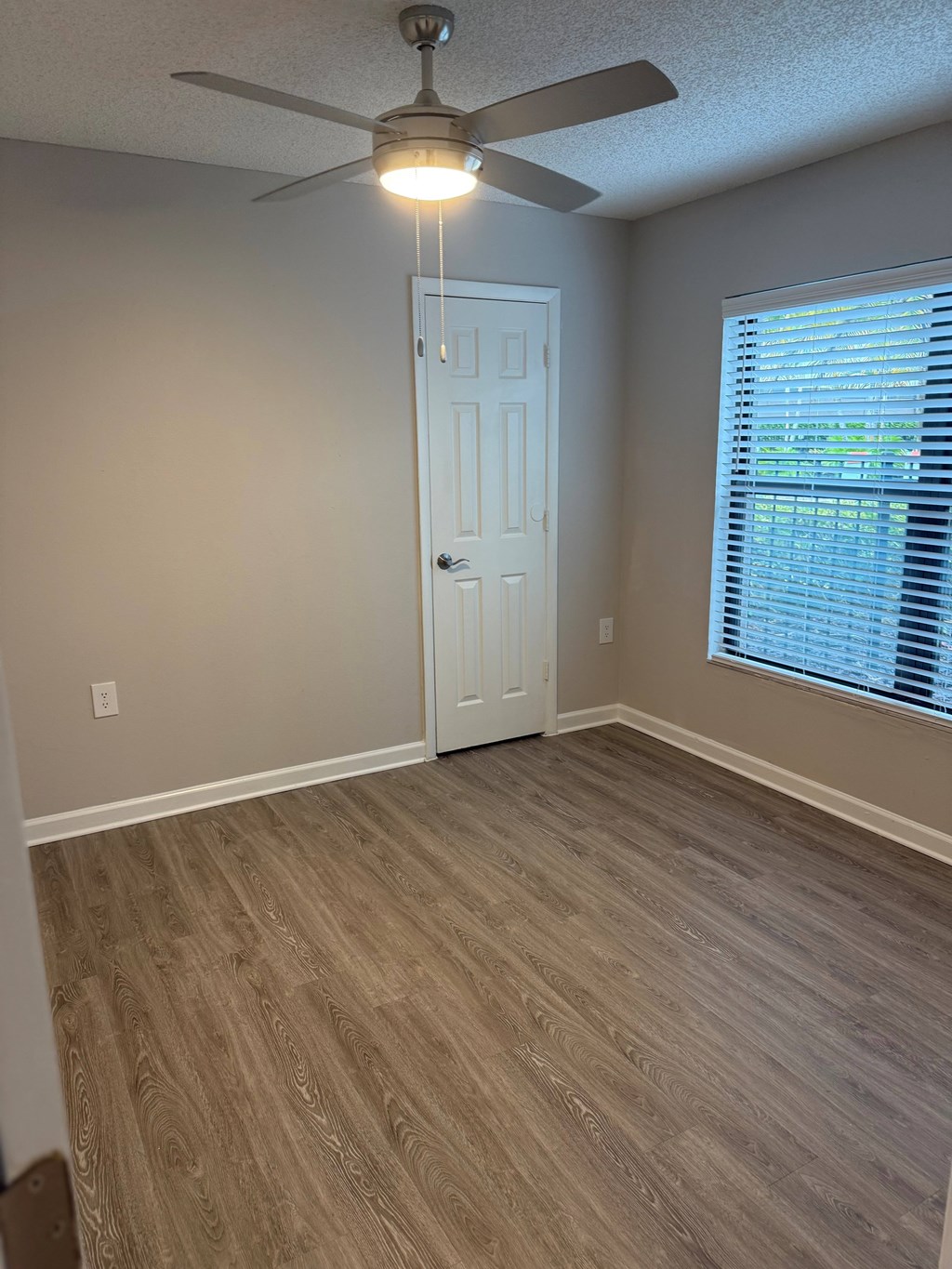 A room with a ceiling fan and a door.