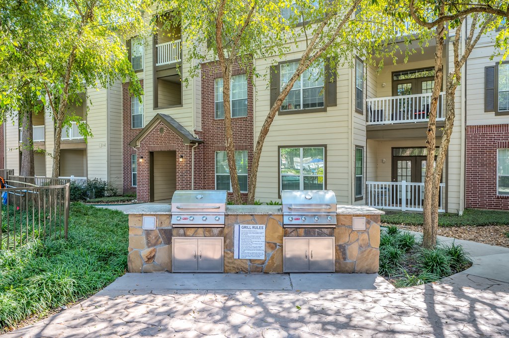 an apartment building with two barbecue grills in front of a sidewalk