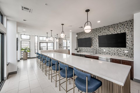 a communal kitchen with blue bar stools and a large white counter top