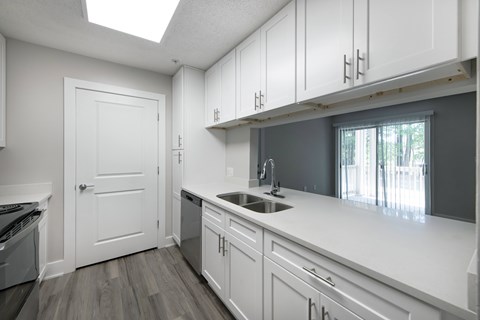 A kitchen with white cabinets and a window.