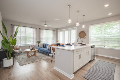 A well-lit, spacious kitchen and living room with a dining table and chairs.